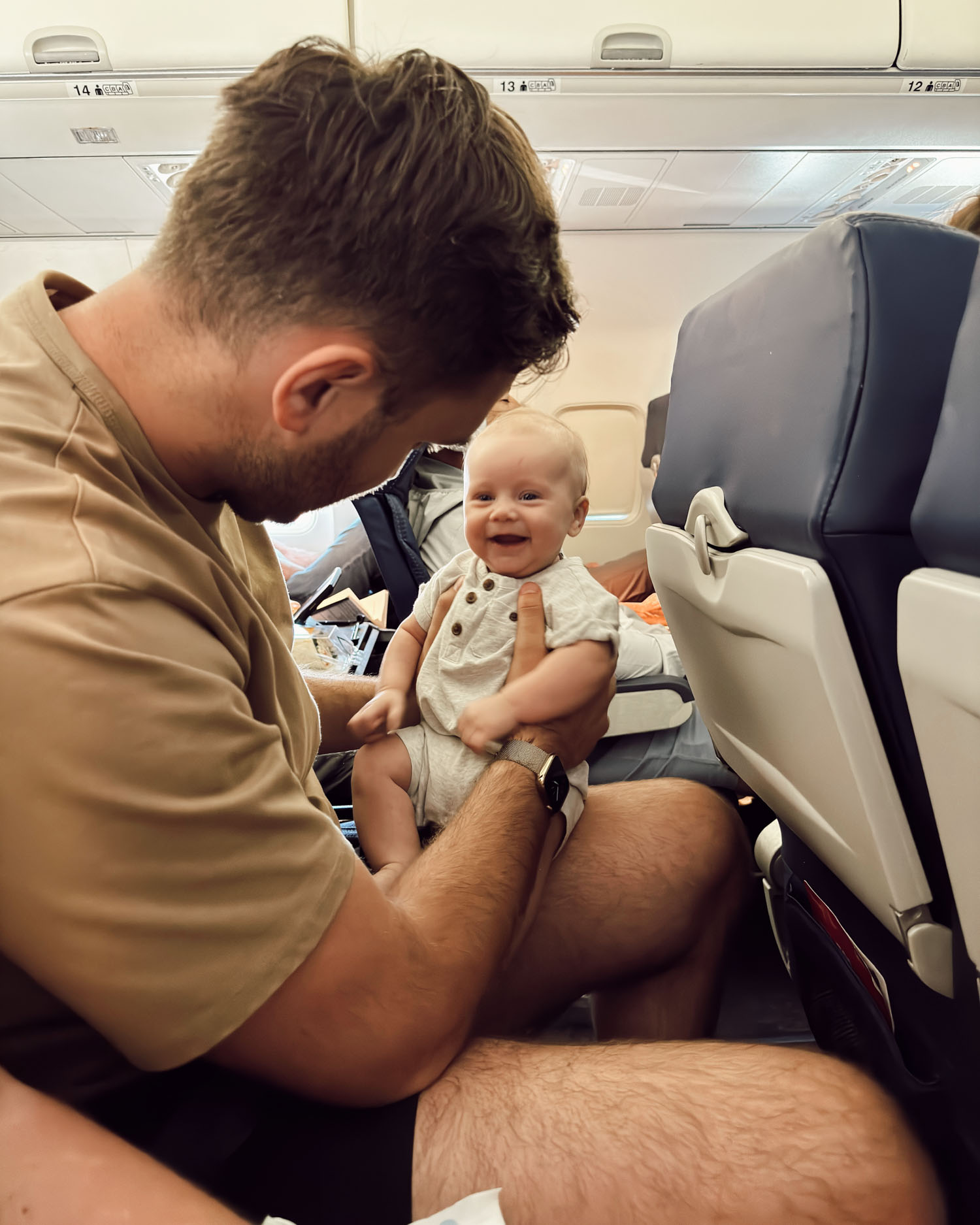 dad flying with smiling infant on lap