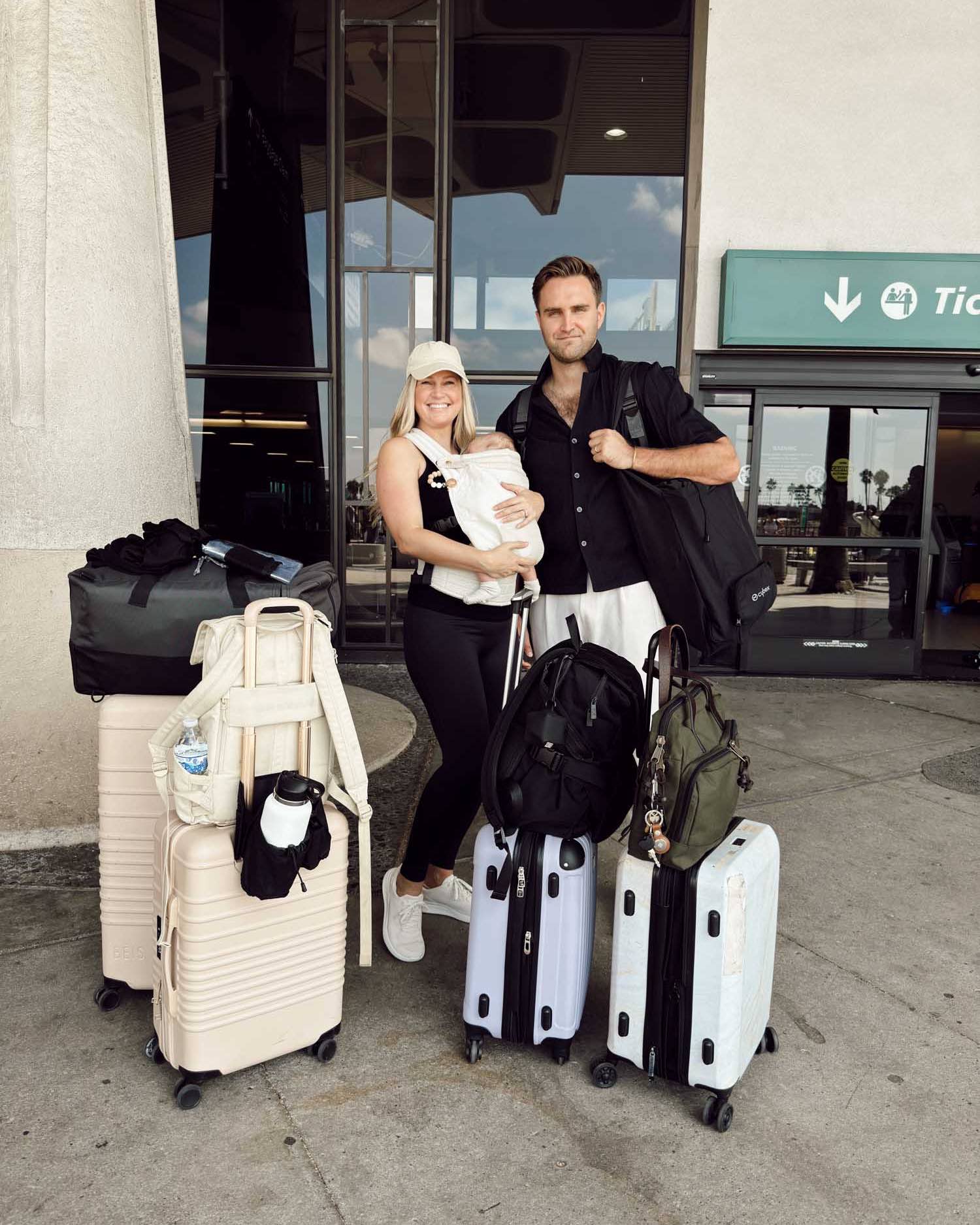 couple with newborn baby taking first flight with lots of luggage outside of the airport