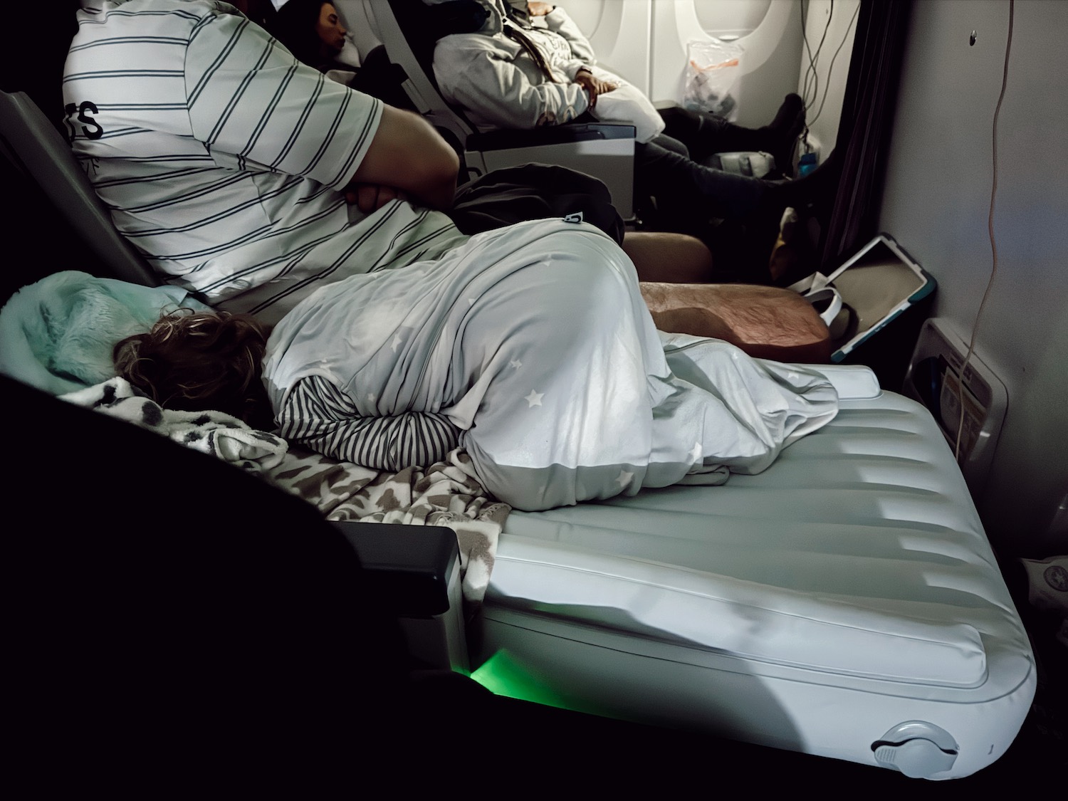 Little toddler boy sleeping in plane on inflatable mattress with blankets and butt up